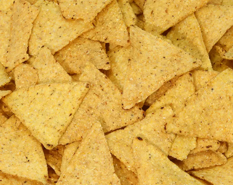 background of yellow tortilla chips made with corn vegetables oils and salt 