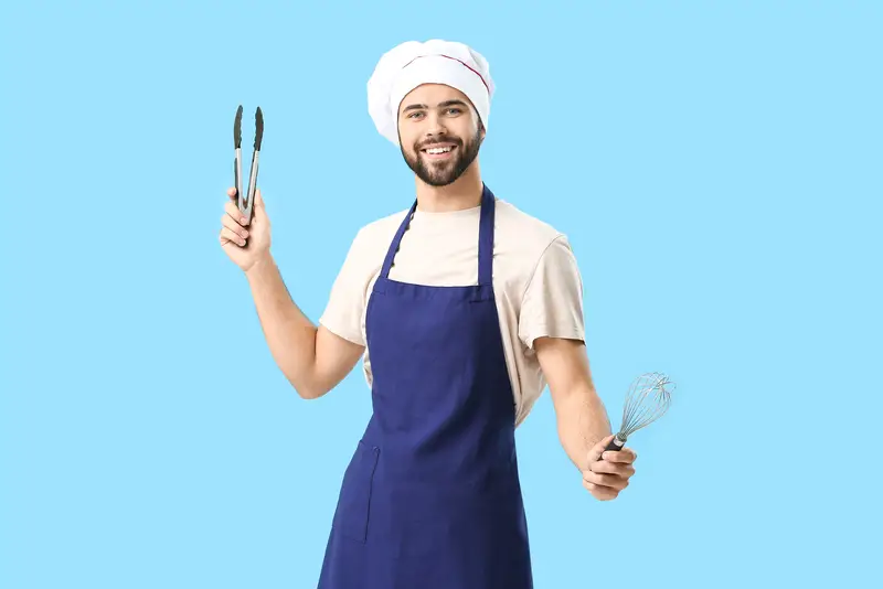 Handsome blue apron male chef on color background